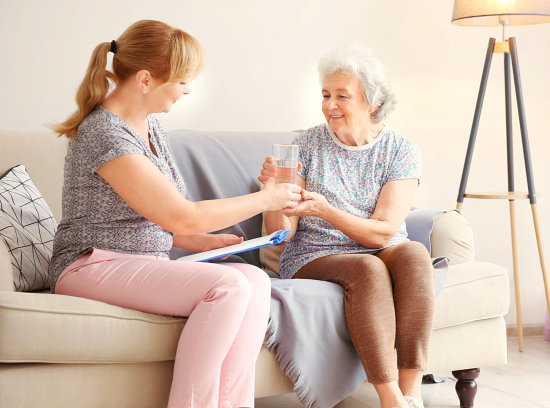 caregiver giving medicine to an elder woman