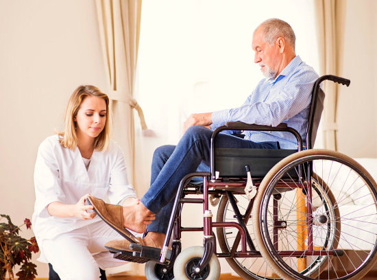 caregiver assisting disabled senior man wear footwear